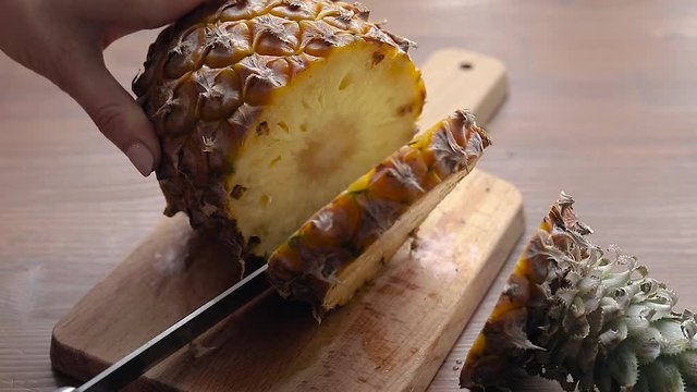 Slicing fresh pineapple on a wooden board