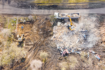 yellow excavator loading dump truck at demolishing site. aerial top view