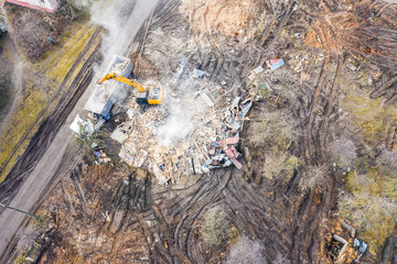 heavy excavator on site of demolished building in city which has been cleared for redevelopment. top down aerial view
