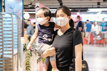 Mother carrying little boy shopping in supermarket wear n95 mask protect COVID 19