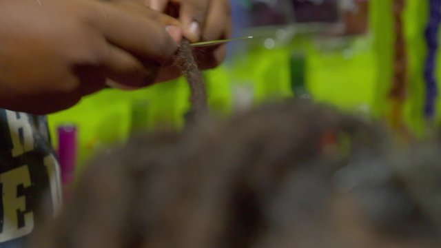 The process of weaving dreadlocks in an Indian salon. Close-up.