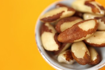 Brazil nut in a ceramic gray cup on a bright orange Background. Wholesome food and snack. Healthy fats ingredient. Vegetarian and vegan food.keto diet. copy space.