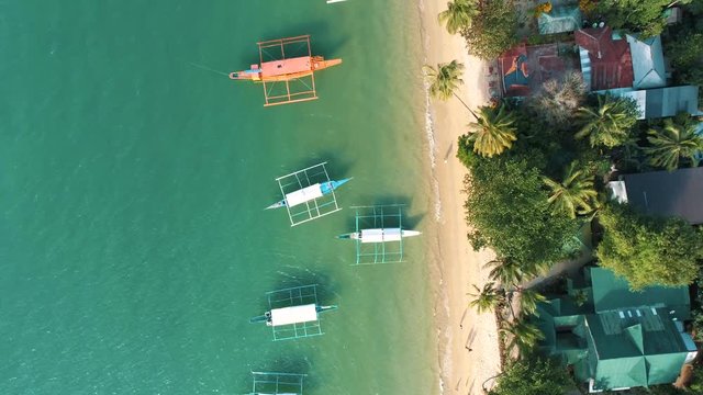 Top drone view of a traditional philippine boats on the surface of the azure water in the lagoon. Seascape with blue bay and boats. El Nido, Port Barton, Palawan. Summer and travel vacation concept.