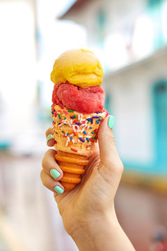  person holding ice cream on cone in front of a street