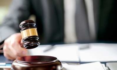 Judge hand holding gavel to bang on sounding block.