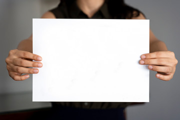 Obraz premium Woman holding empty rectangular sign for message. Hands holding blank paper.