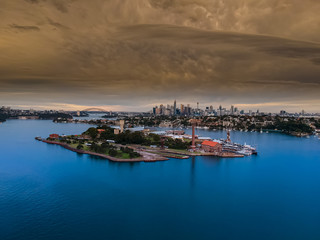 Panoramic drone aerial view over Sydney harbour on a cloudy sunset afternoon showing the nice colours of the harbour foreshore