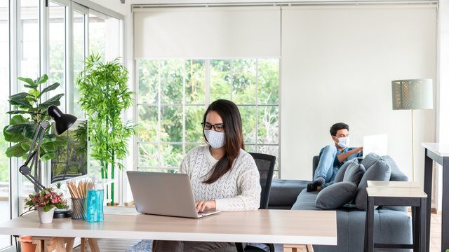 Wife And Husband Working At Home During Lock Down Period Of Corona Virus Out Break With Social Distancing Or Physical Distancing And Wearing Mask To Protect Tion From Virus