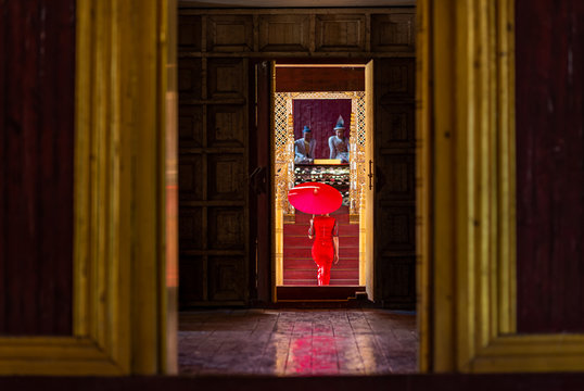 Back View Woman In Red Dress Holding Red Umbrella Walking Through Door In The Temple