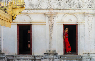 Lady in red dress stand at white door in Myanmar 