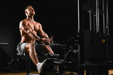Fototapeta na wymiar Fit and muscular man trains chest muscles on a block simulator in a gym. An ideal fitness model, trained in the gym. Sport banner, copy space, fitness motivation.