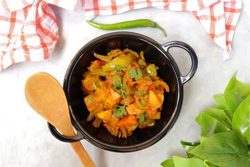 Indian food - Spicy Capsicum and potato stir fried with Indian spices. Aloo and Shimla Mirchi. served in black plate over simple background. 