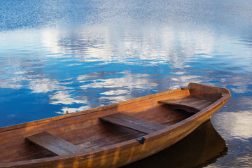 Obraz premium wooden boat on water with clouds
