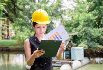 Young woman in hardhat holding clipboard checklist, Quality control concept