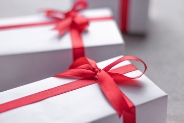 White gift box with red ribbon, black background flat lay for stock image