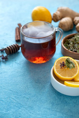 Ginger tea with lemon in glass cup at blue background.
