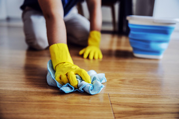 Close up of man waxing parquet. Selective focus on hand with cloth. Rubber gloves on hands. Home...