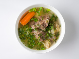 Shurpa soup. Beef with potatoes and carrots in a broth in a white bowl. Top view