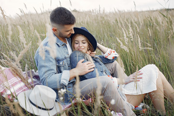 Loving couple in a wheat field. Beautiful blonde with her boyfrinds. They sitting on a blanket