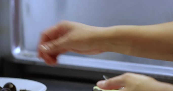 Woman hand rolls chocolate ball then puts on plate - close up - slow motion