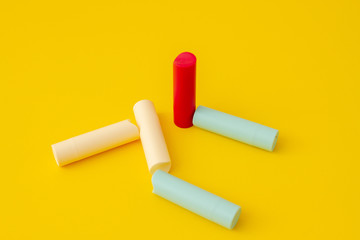 Multi-colored tubes of lipstick on a yellow background in an abstract form and shape