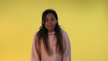 African young woman widely opening her mouth in astonishment on yellow background. She has heard...