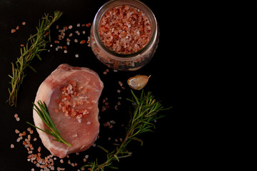 Steak with spices on a black background. Top view. Free copy