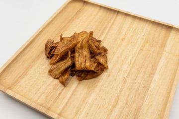 Honey coated crispy baked banana slices on wooden cutting board isolated on white. Thai style homemade healthy snacks.
