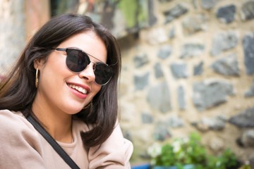 Portrait of young beautiful girl with red lips and sun glasses from middle east country Tunisia is posing to photographee. Blank space and rocky wall background.