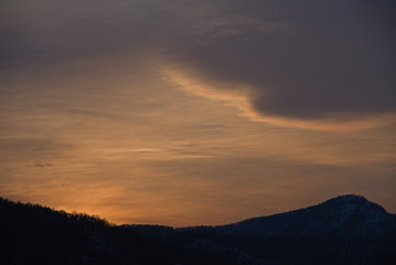 Fototapeta na wymiar 夕暮れの空の雲と山並みのシルエットの風景。