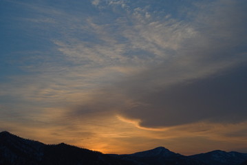 夕暮れの空の雲と山並みのシルエットの風景。
