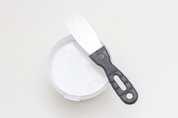 putty knife on tub of white acrylic glazing putty