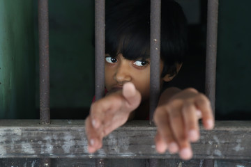 Portrait of a sad innocent child looking out the window. Sad girl looks thoughtfully through the...