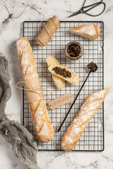 
Fresh baked homemade crusty bread baguette. Two loaves and mashroom pate on metal grate. Top view.