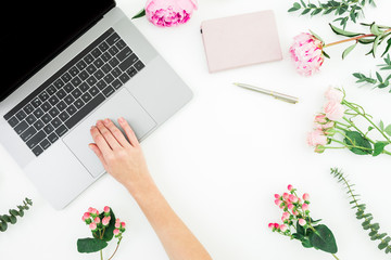 Plakat Woman working with laptop. Female hands with laptop and pink flowers on white background. Top view.