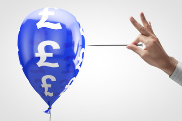Concept: threat to the British currency. Balloon with pound symbol and nail in hand.