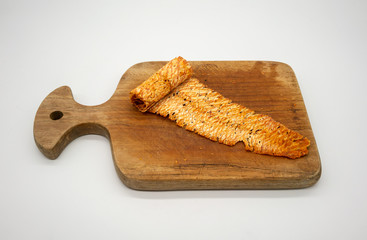 Spicy dried and rolled squid on wooden cutting board isolated on white. Fine chili seasoning seafood snacks.