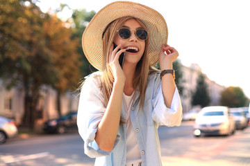 Beautiful young blonde girl using mobile phone while standing outdoors.
