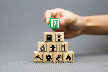Close-up hand choose a wooden toy blocks with fire exit icon for fire safety protection concepts.