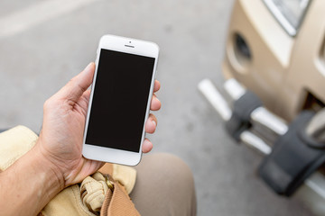 closeup hand holding smartphone with soft-focus and over light in the background