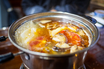 Spicy yak meat in hotpot and fried pig in white plate on wooden table