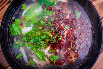 spicy chinese noodle with pork and vegetable in white bowl