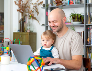 Young attractive father freelance worker working home with baby