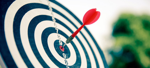 Bullseye or bull's-eye or dart board has dart arrow hitting the center of a shooting target for...