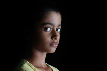 Portrait of an Indian little girl with short hair. Beautiful eye of a child on black background....