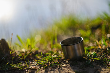 Thermal travel cup isolated with hot drink steaming with a nature background isolated 