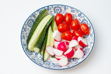 Fresh vegetables for salad in a plate with a blue pattern