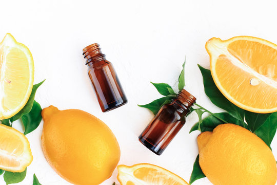 Lemon essential oil, bright yellow citrus fruit slices top view white table, aroma oil, botanical extract for healthy aromatherapy. 