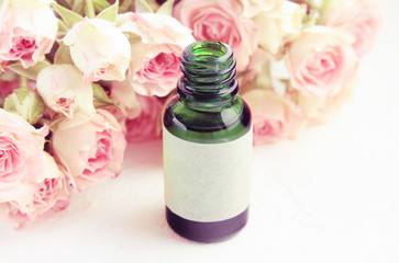 Rose blossom Essential oil, Green glass bottle with empty craft label, closeup, botanical skin care treatment, soft delicate dreamy tone.