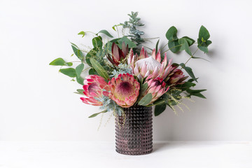 A elegant floral arrangement in a rustic brown vase on a table with a white background. Flower...